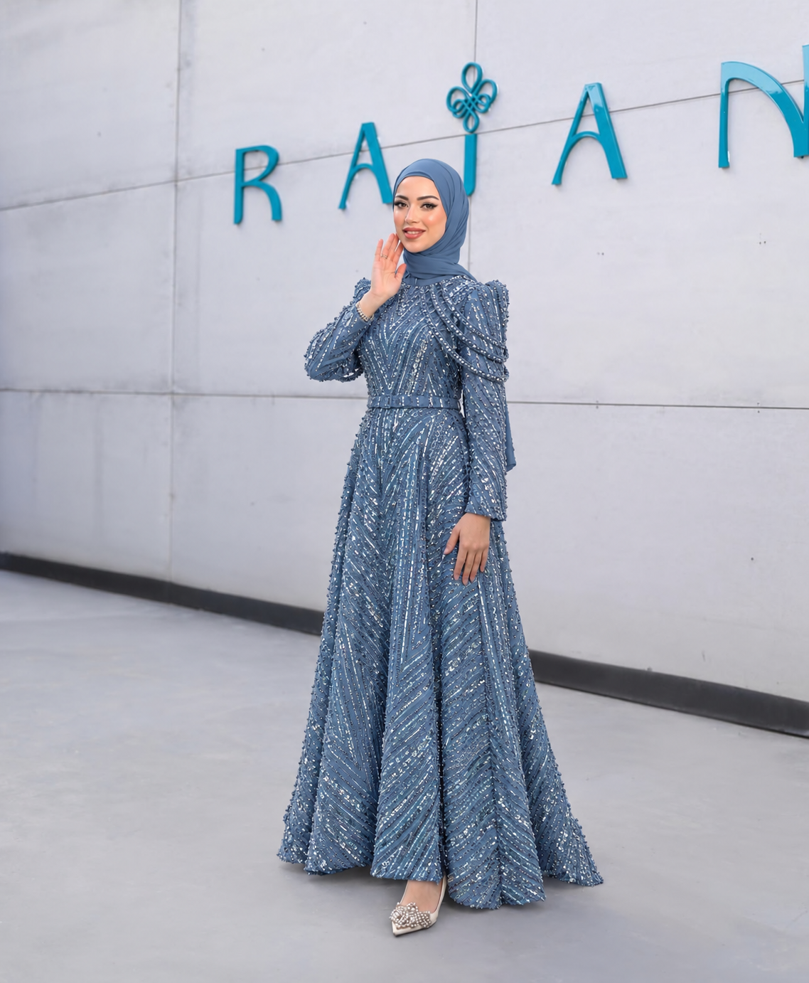 Crystal Cascade Gown shown in blue, with sparkling decoration, layered shoulder drapes, long sleeves and a full skirt.